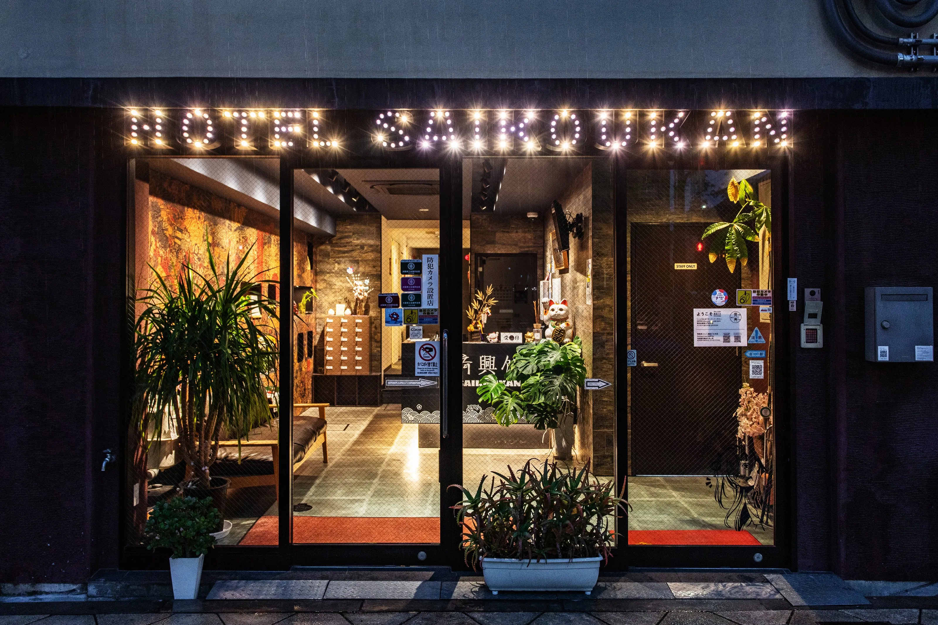 Entrance of Saikoukan at dusk, with the lit Hotel Saikoukan sign