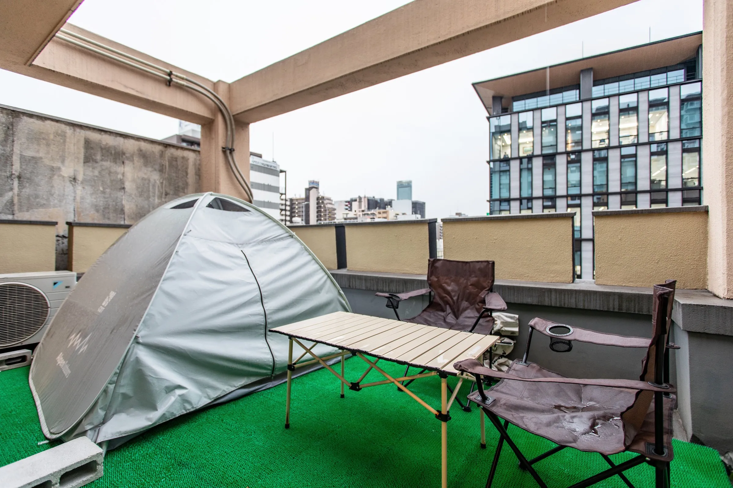 Rooftop terrace with a tent and camp chairs, city skyline behind